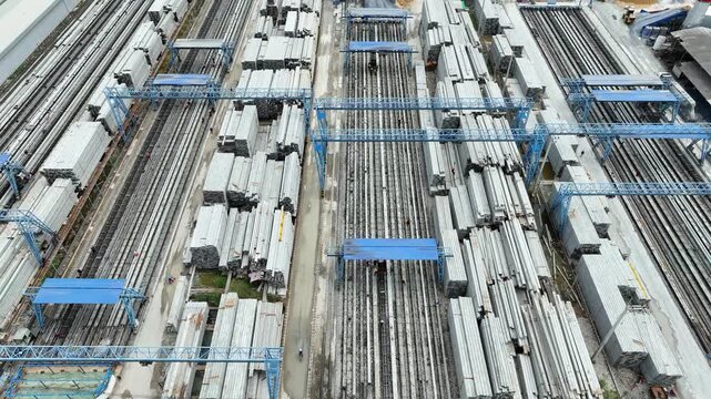 Top view of a concrete factory reveals large quantities of precast columns and production lines, symbolizing mass manufacturing, urbanization and modern construction.
