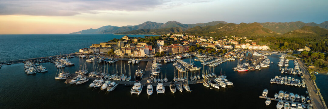 Saint Florent coastal town Corsica island 8K drone panorama Golden hour sunset marina white boats and mountains. High resolution World Print fine art aerial landscape stock photo