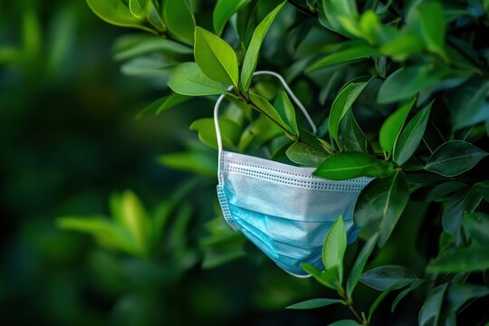 Disposable face mask discarded in lush foliage.