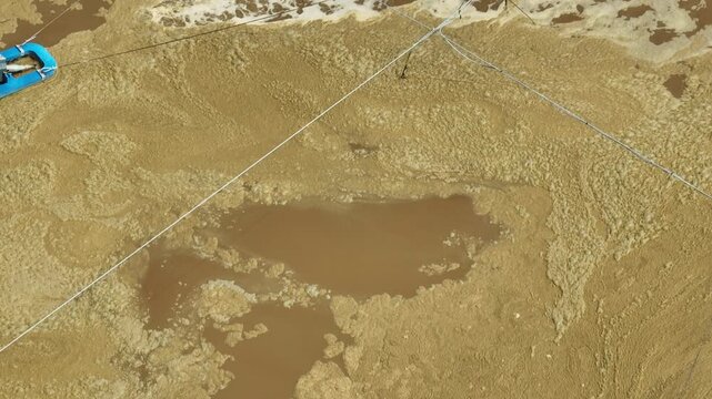 Aerial view captures an industrial wastewater treatment pond with a surface aerator mixing brown water, representing water purification, pollution control, and environmental protection. 4k.
