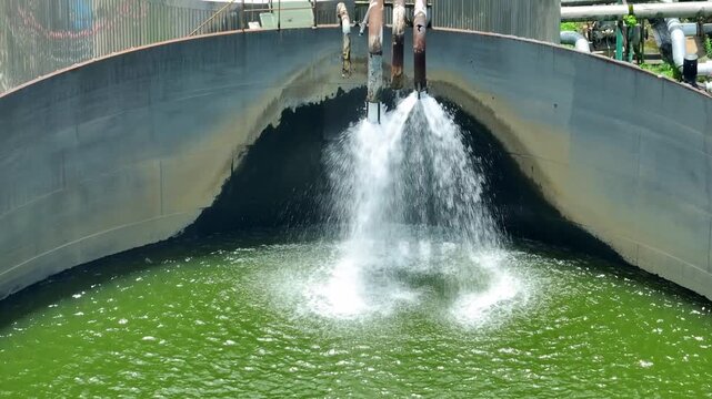 Drone perspective shows an industrial food processing water tank with active inflow, symbolizing water circulation, operational efficiency, responsible resource use and modern manufacturing.

