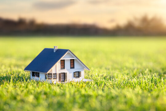 Model detatched house in empty field at sunset background concept for construction and real estate