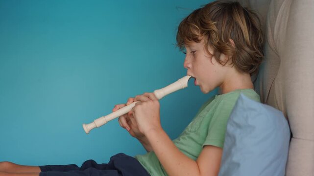 A little boy learns to play the flute at home, practicing with focus and enthusiasm in a cozy, warm setting. A charming scene of early musical exploration, creativity, and childhood growth.