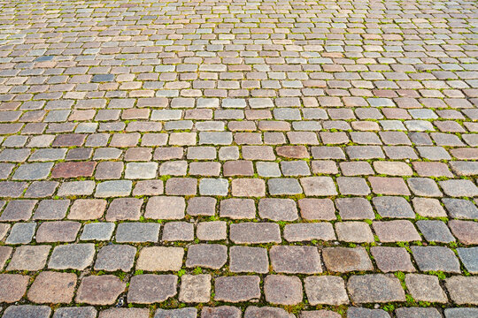 Cobblestones form a weathered street surface. Cobblestones create an old paving pattern. Stone pavement frames cobblestones naturally. Urban background features cobblestones.
