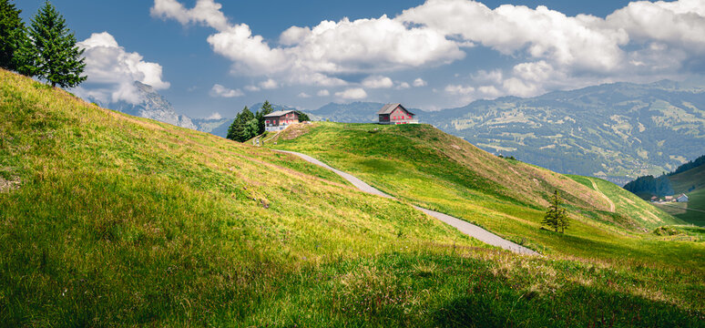 Idyllic Swiss alpine village nestled on a green grassy hillside with scattered clouds