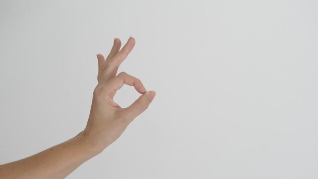 Woman's hand making an OK or approval gesture against a clean white background with extensive negative space