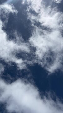 Dark blue sky with white clouds moving slowly in wind