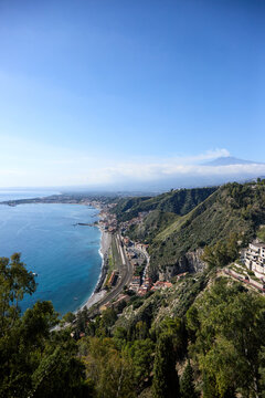 Mount Etna volcano smoking above clouds seen from Taormina in Sicily, Italy.