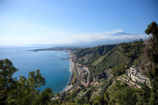 Mount Etna volcano smoking above clouds seen from Taormina in Sicily, Italy.