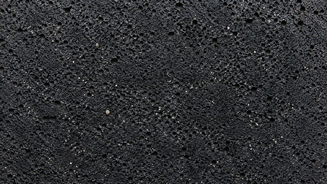 Black volcanic rock texture, porous basalt stone surface, dark charcoal lava background for architectural design