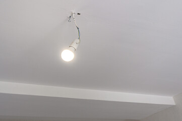 White ceiling with exposed bulb, visible wiring, hook fixture, clean edge, minimal trim, recessed cornice, plain surface, subtle texture © evgeniykleymenov