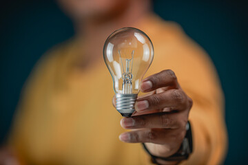 A close-up shot of a man holding a glowing vintage light bulb in an office, symbolizing innovative thinking and entrepreneurial inspiration representing a standout business concept and a creative visi © Treecha