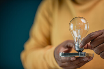 A close-up shot of a man holding a glowing vintage light bulb in an office, symbolizing innovative thinking and entrepreneurial inspiration representing a standout business concept and a creative visi © Treecha