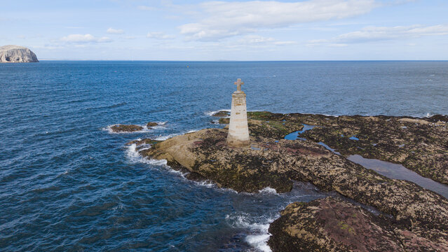 Historic St Baldreds Cross monument on rocky outcrop near Seacliff Beach North Berwick with Bass Rock