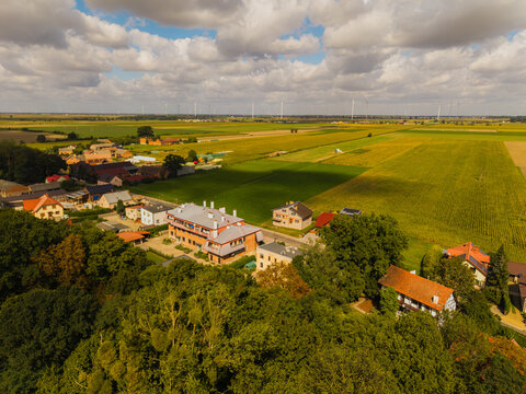 Aerial view of Palac w Pakoslawiu surrounded by lush green fields, trees, and rural buildings in Nowy Tomysl, Wielkopolskie, Poland.