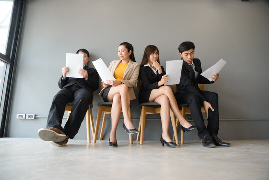 Business professionals in group holding documents and paperwork, showing team, employment, and recruitment concept in office workplace, with corporate colleagues sitting together and copy space.