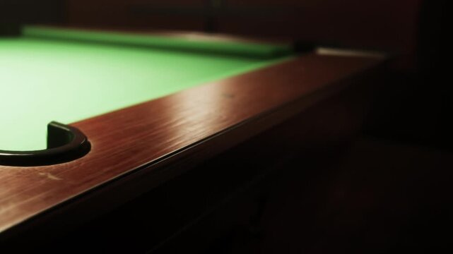 A polished pool table with a vibrant green felt surface sits ready for action in a dimly lit room.
