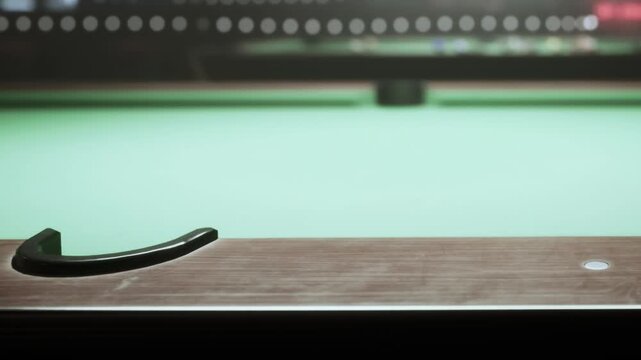 A close up view of a pool table shows its smooth green felt. The surrounding dimly lit room hints at an exciting game ahead. Balls are neatly arranged, preserving the anticipation.