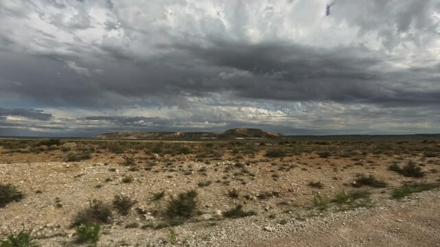 Panning shot of arid landscape and plateau from moving vehicle