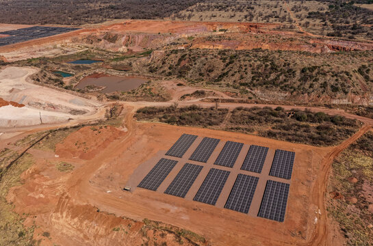 Aerial view of a solar panel array providing renewable energy to remote mining operations in a rugged landscape with red earth and dirt roads in Polokwane, Limpopo, South Africa.