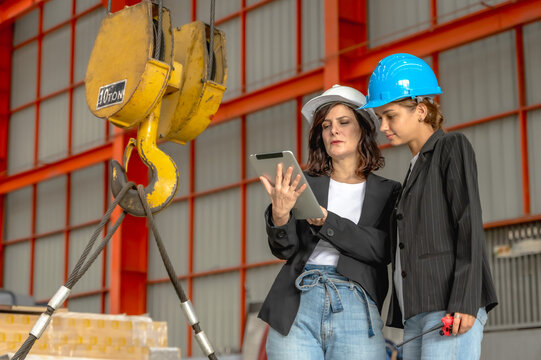 Two female quality control inspectors monitoring and assessing the environmental conditions inside a zinc sheet manufacturing plant