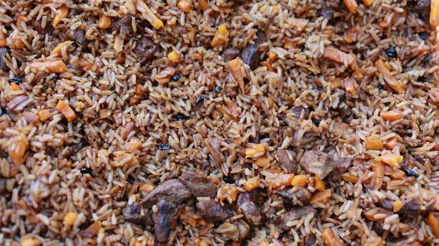 Traditional pilaf with rice, meat and carrot close up. Oriental cuisine dish cooked in cauldron. Homemade food texture background for recipe and menu design