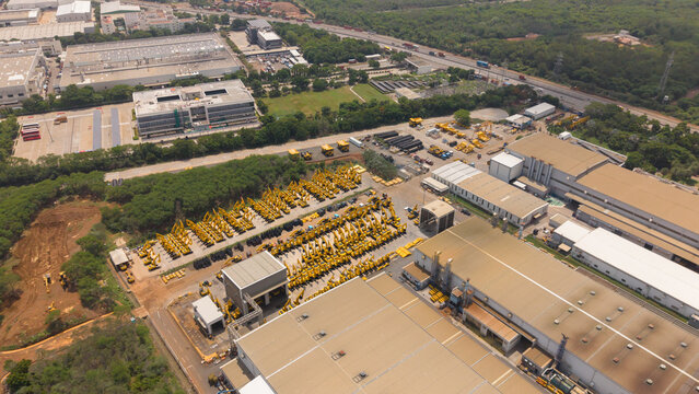 Aerial view of yellow construction cranes parked in rows at a manufacturing facility in India.