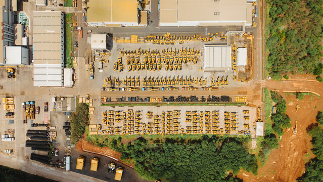 Aerial view of cranes manufacturing facility with rows of yellow construction machinery parked in an industrial yard in India.