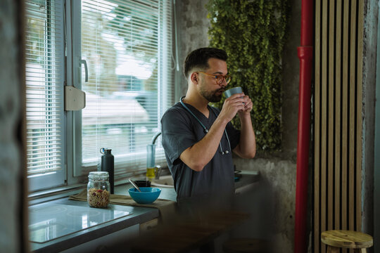 Male nurse healthcare professional drinking coffee on break at home