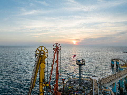 Aerial view of an industrial loading arm and jetty structure extending into the sea at sunset in Ratnagiri, Maharashtra, India.