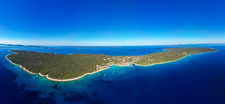 Aerial drone panorama of the western part of Silba Island, Croatia, surrounded by the crystal-clear Adriatic Sea. The picturesque coastal village, turquoise shoreline and Mediterranean vegetation