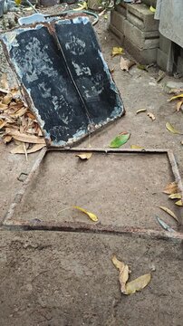 Old cistern cover plate in a backyard garden surrounded by dry leaves
