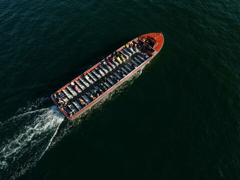 Aerial view of a canal boat filled with passengers cruising through the dark water in Copenhagen, Denmark.