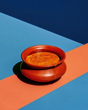 Earthen handi of kheer with a matte terracotta finish, set against a deep indigo and purple background for dessert packaging and graphic design