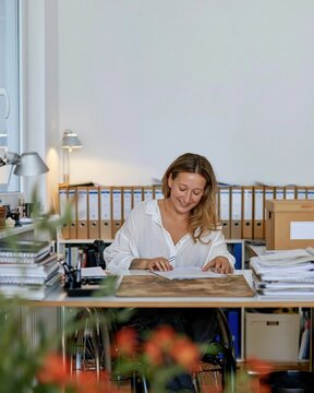 Professional woman working at a desk with a worn blotter and documents in a muted sage green office for legal and notary services