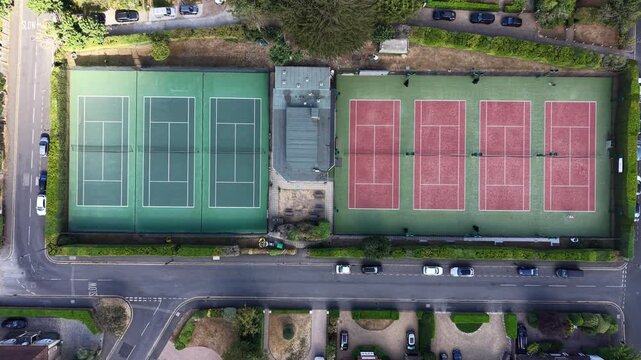 4K UHD drone tracking shot transitioning from one tennis court complex to an even larger tennis court facility at Raphael Park, Romford, England. Continuous flight path under beautiful lighting