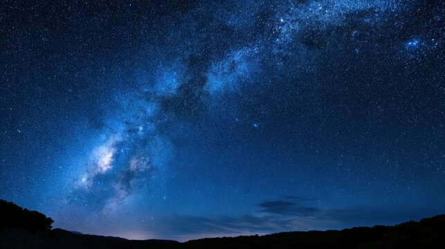 Celestial panorama of a deep blue night sky showing Milky Way and distant galaxies