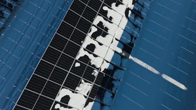 Snow partly blocks dark solar panels, revealing winter energy vulnerability