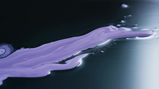 Purple fluid ribbons spread and ripple across a dark reflective surface. Motion graphics, creative transition, and beauty campaign design.