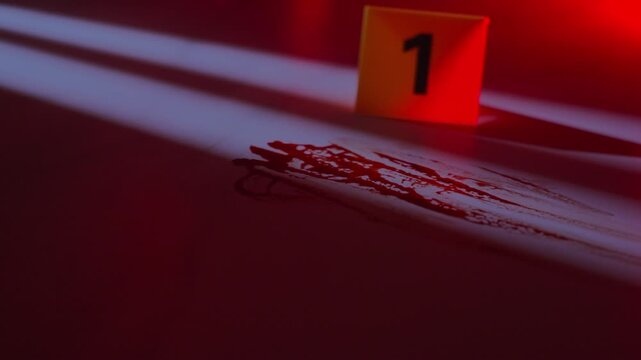 Gloved hand of forensic investigator placing yellow evidence marker near blood streak on floor with moonlight, window shadows, and flashing police lights in dark crime scene, close up