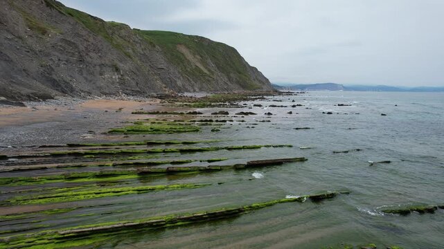 Aerial view of the rocky coastline with green mossy formations and cliffs in Bilbao, Basque Country, Spain.