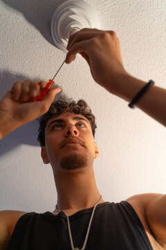 Young person performing an electrical repair on the ceiling with a screwdriver