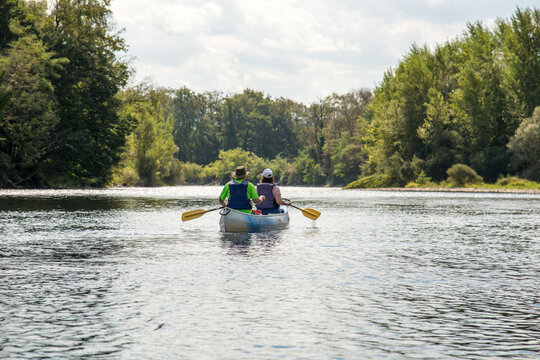 France, Lot, Dordogne River.  A couple paddling canoe on the calm river.