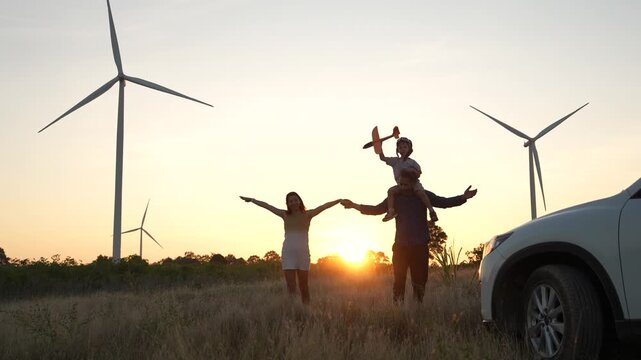 Family happiness and bonding at sunset, relaxation and renewable energy with innovation, wind turbines and sustainable energy, travel, relaxation and the environment.	
(VDO 4K)