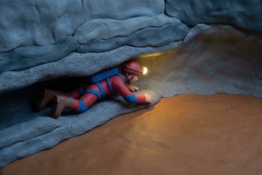 Spelunking explorer in cave tunnel with headlamp and claymation style