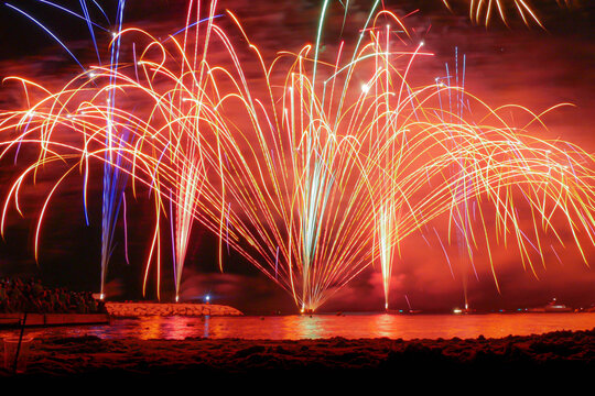 Bright red and golden fireworks exploding against a dark night sky