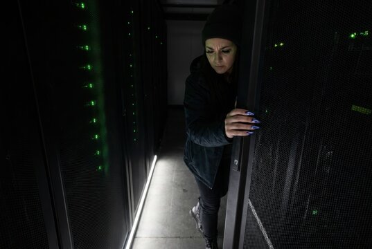 Datacenter technician inspecting server racks in a dark corridor