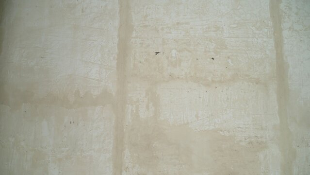 Raw unfinished concrete wall with patches of beige plaster and vertical joint lines for texture background