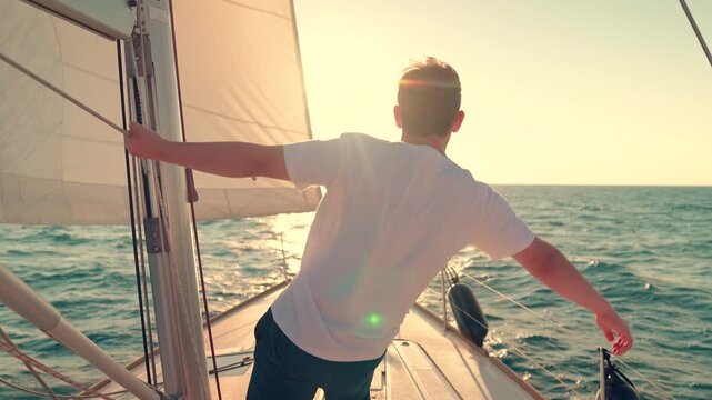 Yacht with sail gliding sea, cabin boy on deck gazing sun. Ships captain sailing ocean, raising hands. Sail towards your dream, adventure. Man sailing on yacht under white sail. Sea voyage free wind