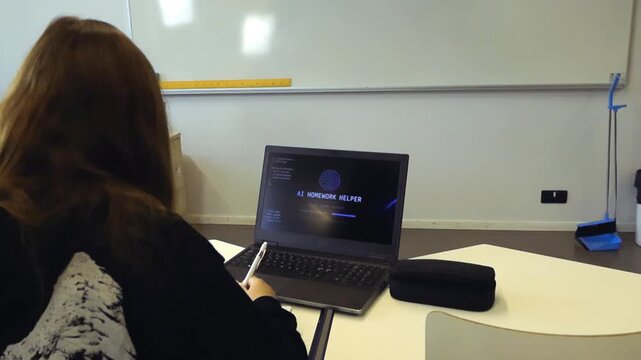 Female student sitting at her desk in a classroom, using a modern laptop with an artificial intelligence homework helper program to complete her school assignments and improve her learning